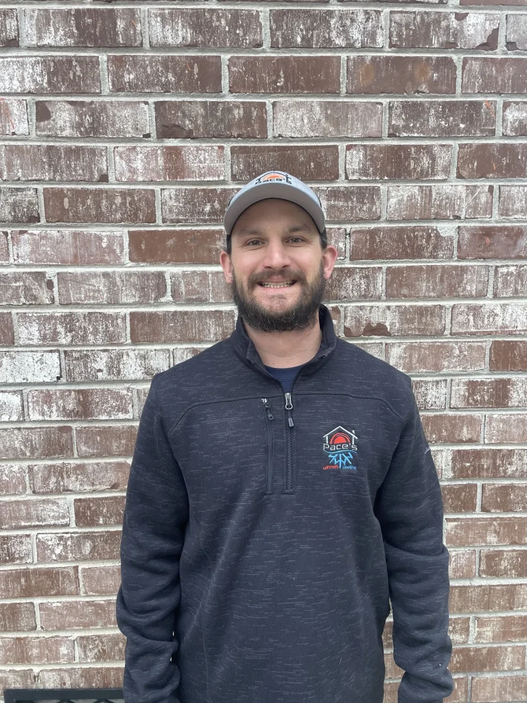 Man in a Pace's Comfort Cooling branded jacket standing against a brick wall, representing HVAC expertise and local service commitment in South Carolina.